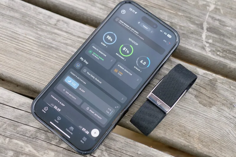 WHOOP 5.0 app recovery and strain interface beside fitness band