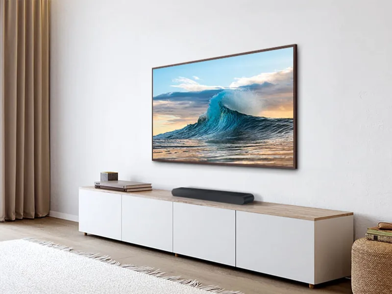 Samsung HW-S60D positioned on a TV console beneath a wall-mounted television