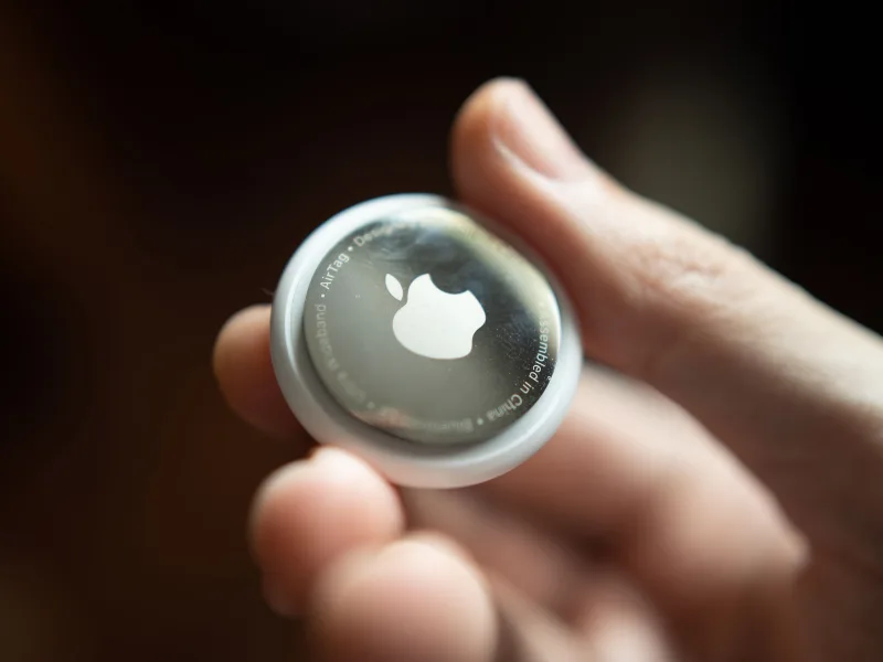 Apple AirTag held in hand showing compact tracker size